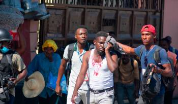 Un periodista herido recibe ayuda tras ser alcanzado por un bote de gas lacrimógeno disparado por la policía en Puerto Príncipe, Haití.