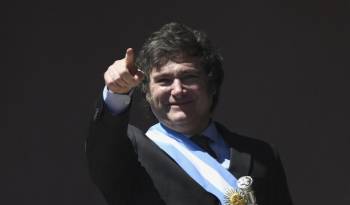 El nuevo presidente de Argentina, Javier Milei, hace gestos desde un balcón del palacio de gobierno de la Casa Rosada.