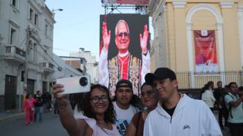 Personas toman una fotografía con la imagen del papa León XIV de fondo en la plaza central de Chiclayo (Perú).