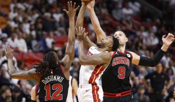 Ayo Dosunmu (i) y Nikola Vucevic, de los Chicago Bulls, en acción ante Haywood Highsmith de los Miami Heat en el partido de este viernes de la NBA en Miami, Florida. EFE/ Rhona Wise
