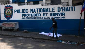 Un hombre pasa junto al cuerpo de un oficial de policía asesinado en medio de la violencia de pandillas en Puerto Príncipe, Haití.