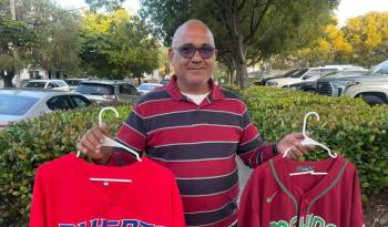 El vendedor José Godoy muestra unas camisetas de béisbol de Puerto Rico y México.