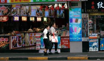 Personas caminan frente a restaurantes en una calle de Shanghai, China.