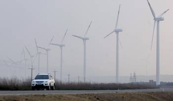 En la imagen de archivo, un vehículo pasa cerca de varios molinos de viento en una central eólica en la ciudad de Weihai, en la provincia oriental china de Shandong.