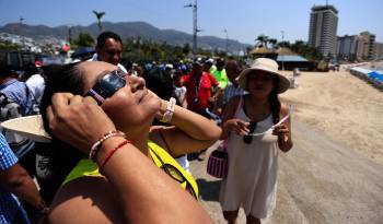 Personas observan un eclipse solar este lunes, en el balneario de Acapulco (México).