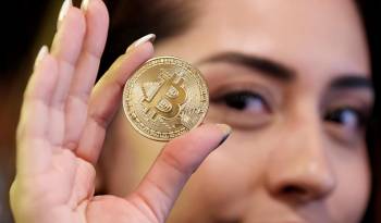 Una mujer sostiene una moneda de bitcoin en una imagen de archivo.