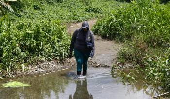 Una migrante atraviesa un riachuelo en Bajo Chiquito (Panamá), después de días de caminata para cruzar la peligrosa selva del Darién, frontera entre Colombia y Panamá.
