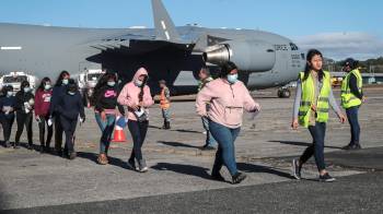 Fotografía del 24 de enero de 2025 de un grupo de migrantes guatemaltecos deportados caminando por la pista de la Base Aérea de Guatemala, en Ciudad de Guatemala.