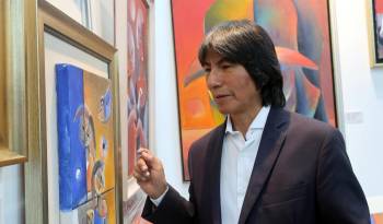 El pintor ecuatoriano Olmedo Quimbita observa unas obras durante la feria 'AQ Arte', este jueves 15 de agosto de 2024 en Quito.