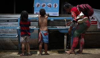 Fotografía de archivo fechada el 3 de mayo de 2024 que muestra a una mujer y dos niños migrantes tras cruzar la selva del Darién en Lajas Blancas.