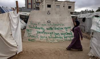 Una refugiada en Gaza pasa por delante de una inscripción de agradecimiento por las manifestaciones propalestinas en las universidades norteamericanas.