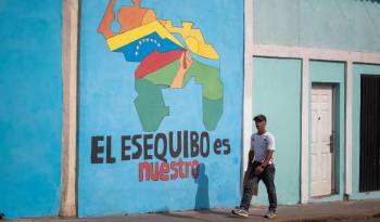 Transeúntes caminan frente a un mural con el mapa de Venezuela que dice El Esequibo es nuestro, en Caracas (Venezuela), en una fotografía de archivo.