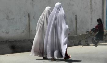 Mujeres afganas vestidas con burka caminan por una carretera en Kandahar, Afganistán.