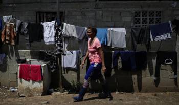 Una migrante camina frente a ropa colgada en una estación migratoria, luego de cruzar la selva del Darién con rumbo a Estados Unidos.