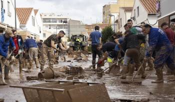 Varias personas colaboran en la limpeza de una calle afectada en la localidad de Utiel, este viernes 1 de noviembre.