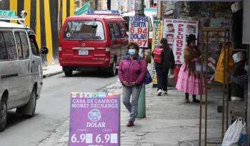 Escena de una calle con transeúntes frente a una casa de cambio en Bolivia.