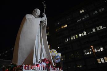 Globos están atados a la estatua de Juan Pablo II, donde las personas llevan velas y acuden a rezar afuera del hospital Gemelli, en Roma, donde el papa Francisco está hospitalizado.