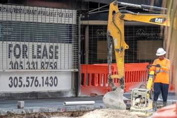 Un trabajador de la construcción trabaja frente a una tienda en el centro de Miami.