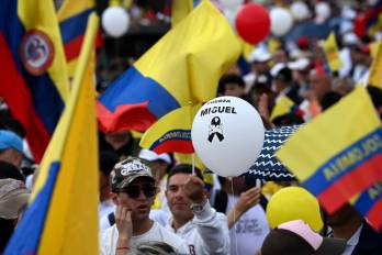 La gente ondea banderas nacionales durante la llamada “Marcha Silenciosa” para expresar su apoyo a la salud del senador Miguel Uribe Turbay.