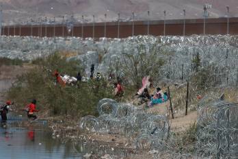 Migrantes llegan a una orilla del Río Bravo sembrada con alambre de púas en Cudad Juárez, Chihuahua (México).