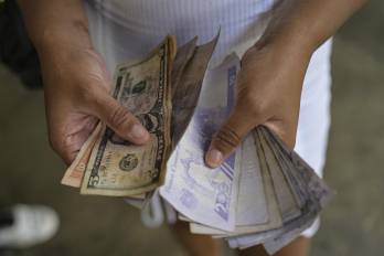 Una mujer cuenta billetes de bolívares y dólares estadounidenses en el barrio de Petare, en Caracas.