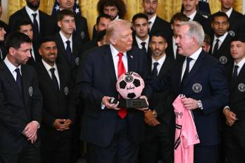 Trump sostiene un balón de trofeo mientras conversa con el propietario gerente del Inter Miami, Jorge Mas, durante un evento para el Inter Miami CF, ganador de la Copa de la Major League Soccer 2025, en el Salón Este de la Casa Blanca, en Washington, D. C.