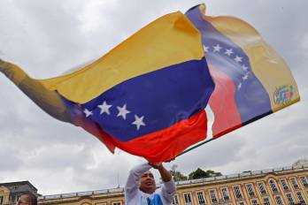 Fotografía de archivo en donde un hombre agita una bandera venezolana.