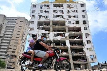 Personas circulan en motocicleta frente a un edificio de apartamentos dañado en Catia La Mar, estado La Guaira, Venezuela, el 16 de julio de 2026.