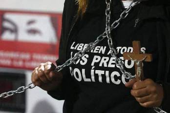 Una persona sostiene un crucifijo y unas cadenas para exigir la liberación de los presos políticos.
