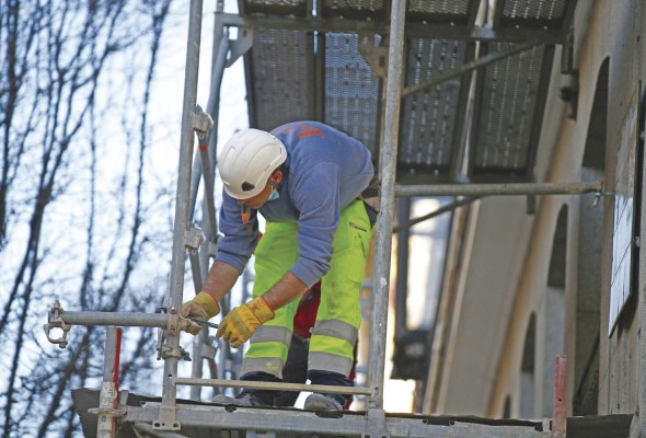 Un obrero de la construcción trabaja sobre un andamio en una calle en Madrid.