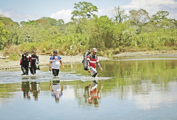 Personas migrantes cruzan el río Tuquesa, en Darién (Panamá).