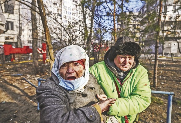 Una mujer es evacuada de un edificio de apartamentos en llamas, en Kiev, el 15 de marzo de 2022, después de que los ataques en áreas residenciales mataran al menos a dos personas, dijeron los servicios de emergencia de Ucrania.