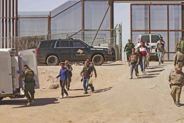 Fotografía general donde se observa a migrantes en un campamento junto al muro fronterizo en Tijuana, Baja California (México).