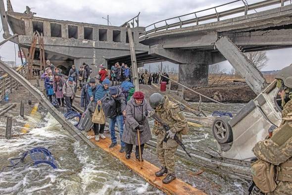 Decenas de civiles cruzaban por un puente semidestruido por los ataques rusos en la ciudad de Irpin, en la región ucraniana de Kiev, el pasado mes de marzo.