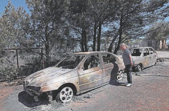 Una mujer observa los coches quemados del incendio acaecido en Anthousa, cerca de Atenas, Grecia.