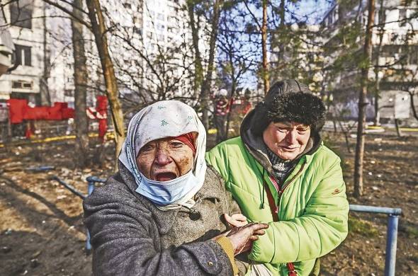 Una mujer es evacuada de un edificio de apartamentos en llamas, en Kiev, el 15 de marzo de 2022, después de que los ataques en áreas residenciales mataran al menos a dos personas, dijeron los servicios de emergencia de Ucrania.