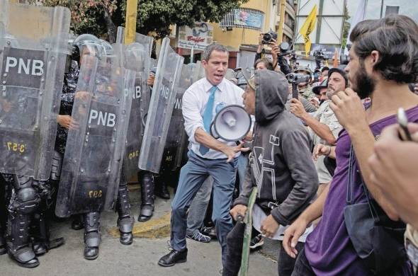 Juan Guaidó anima a sus simpatizantes frente a un cerco policial en Caracas.
