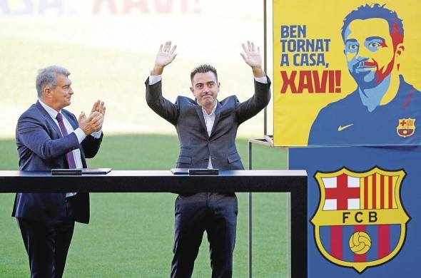 El nuevo entrenador del FC Barcelona, Xavi Hernández, junto al presidente del club, Joan Laporta (i), saluda a los aficionados que se citaron en las gradas del Camp Nou durante el acto de presentación como entrenador blaugrana.