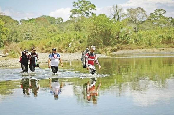 Personas migrantes cruzan el río Tuquesa, en Darién (Panamá).