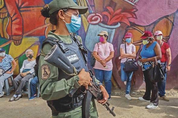 Una militar vigila mientras personas hacen fila para ingresar a un centro de vacunación contra la covid-19, en Caracas (Venezuela).