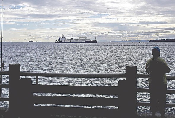 Un hombre pesca en un muelle frente al Canal de Panamá.