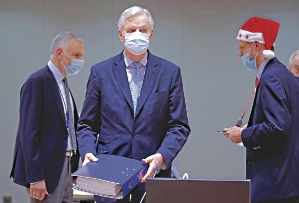 El negociador comunitario Michel Barnier (c) deposita en la mesa el archivador con las 2,000 páginas del acuerdo alcanzado con el Reino Unido, en presencia de delegados griegos, durante la reunión extraordinaria convocada este viernes en Bruselas para explicar los detalles del acuerdo del Brexit.