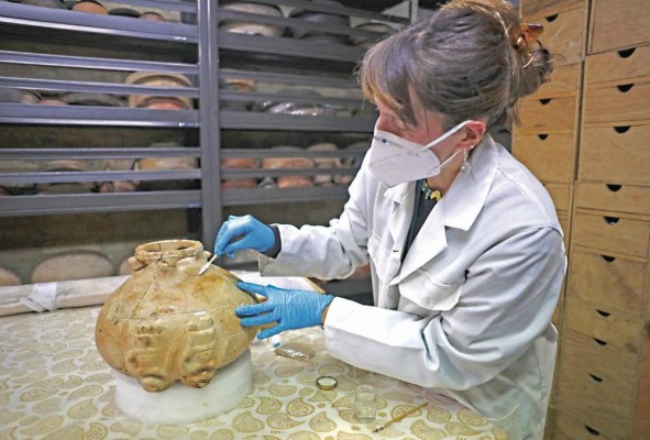 La restauradora Carla Medina analiza una vasija de barro repatriada desde Italia