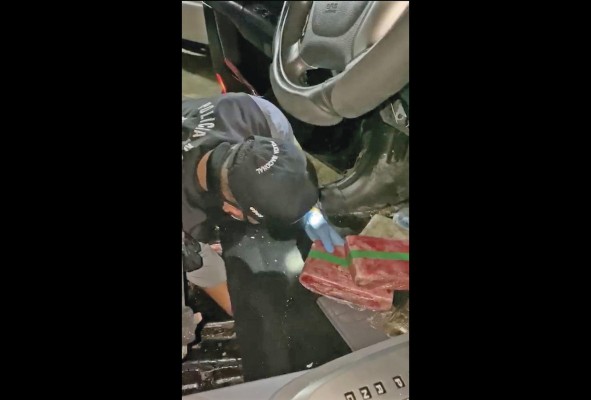 Agentes policiales extraen la droga del auto.