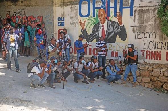 Un grupo de personas se reúne en la calle junto a un mural del asesinado presidente Jovenel Moïse hoy, en Puerto Príncipe.