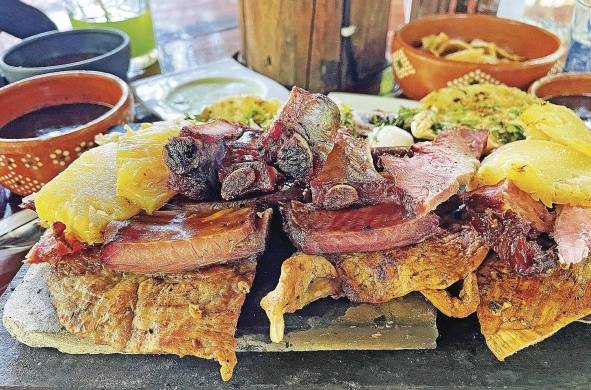 Vista de un platillo preparado con carne ahumada, longaniza y 'poc chuc', servido sobre una tabla el 23 de julio de 2022 en el restaurante Achiote, poblado de Tikuch, Valladolid, estado de Yucatán.