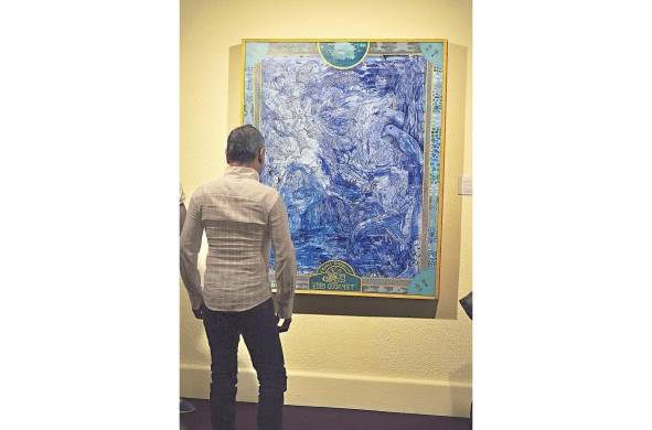 Un hombre admira una obra del pintor Ureña Ramos.