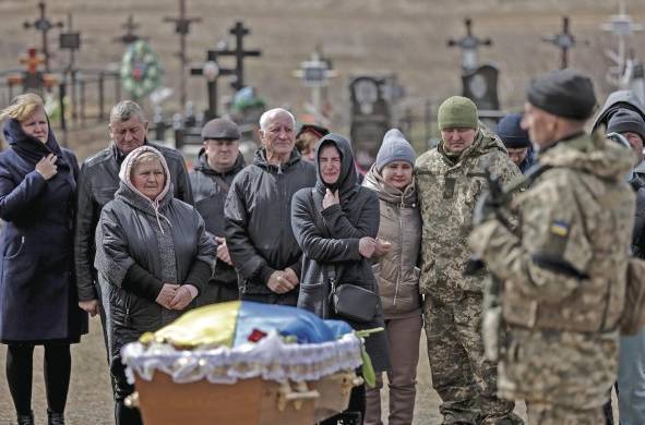 Fotografía de archivo tomada el 27/03/2022, de familiares y compañeros que se despiden de un soldado en el cementerio de Yuzhne.