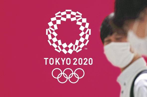 Fotografía de archivo de personas con tapabocas pasando frente a un cartel con la imagen de los Juegos Olímpicos Tokio 2020.