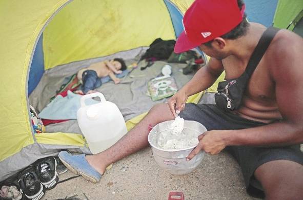 Un migrante venezolano le sirve comida a su hijo en la comunidad de Bajo Chiquito, en Darién.
